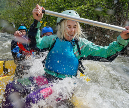 Extreme rafting female with oar splashed by the water of the river