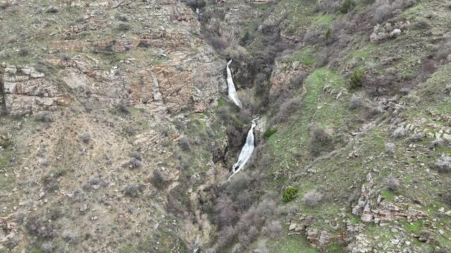 4K aerial drone footage of multi level waterfall in rocky mountain canyon with flowing stream, natural landscape.