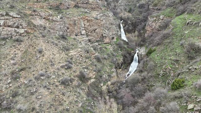 4K aerial drone footage of multi level waterfall in rocky mountain canyon with flowing stream, natural landscape.