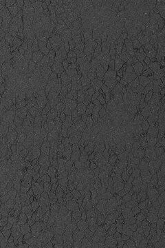 Dark grey asphalt texture with fine surface cracks and weathered stone road details.