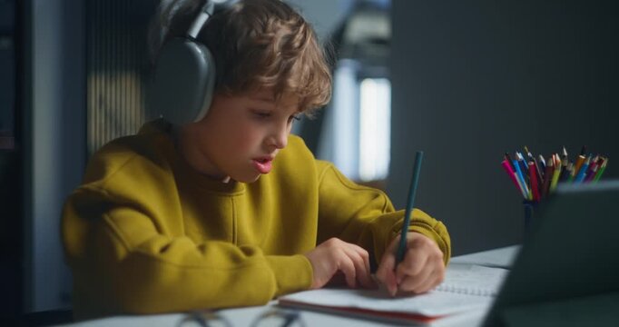Focused Boy With Headphones Studying. Young Male Student Concentrating On Homework In Peaceful Setting