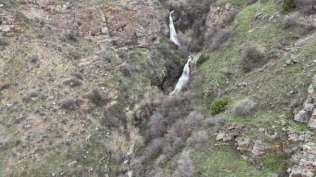 4K aerial drone footage of multi level waterfall in rocky mountain canyon with flowing stream, natural landscape.