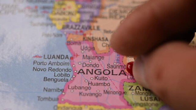 Close-Up World Map Shot Showing Red Pin Highlighting Angola Pointed by Hand 4K 60fps