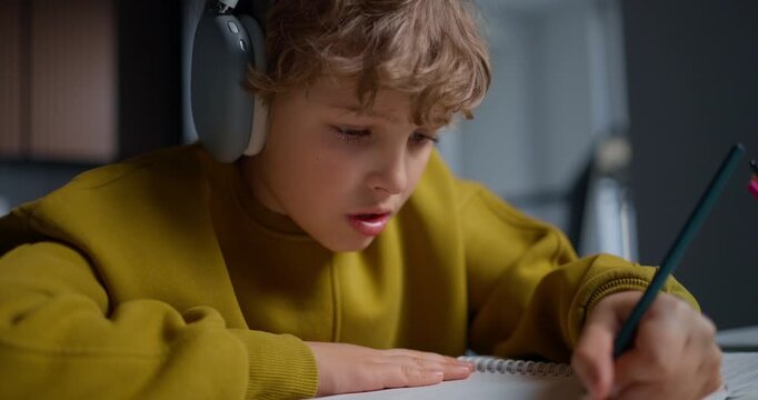 Student Concentrating On Homework. Teenager With Headphones Diligently Working On His Assignment