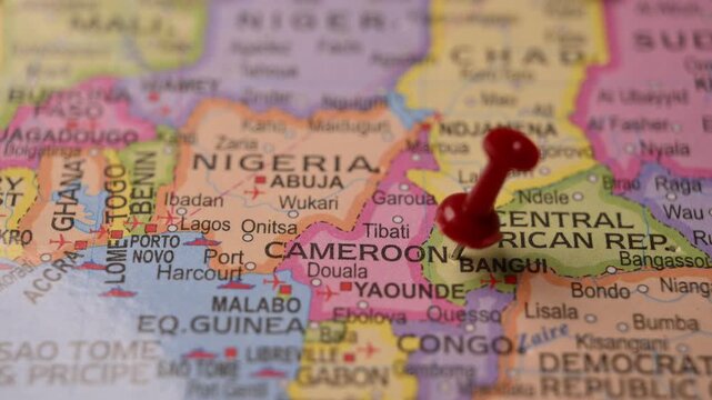 Man Marking Cameroon Location with Red Pin on Paper World Map in 4K 60fps Close-Up Travel Concept