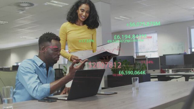 Woman opening black folder and man typing and pointing at laptop while reviewing finance overlays