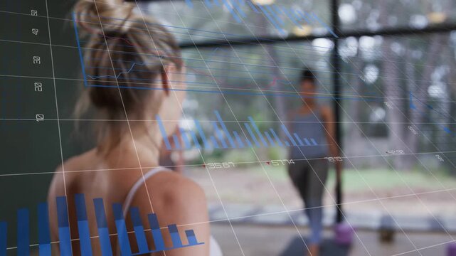 Instructor pointing, guiding participants into lunges in fitness class while blue charts tracking
