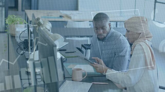 Woman pointing and tapping tablet creating data overlays across desk while man leaning thinking