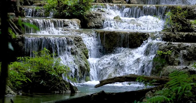 Beautiful deep forest Erawan waterfalls flowing over tiered rocks