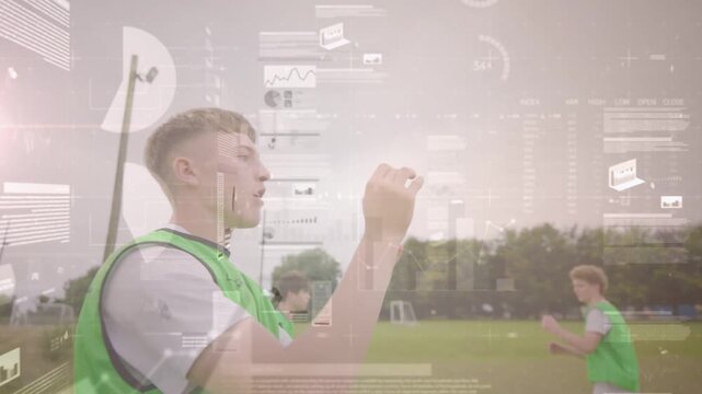 Teen boy catching, lifting soccer ball after teammate toss, football drill with HUD overlaying play