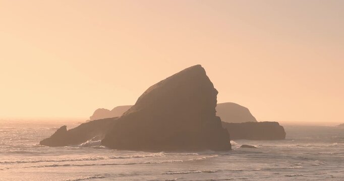 Golden hour light shining on coastal rock formations in Oregon