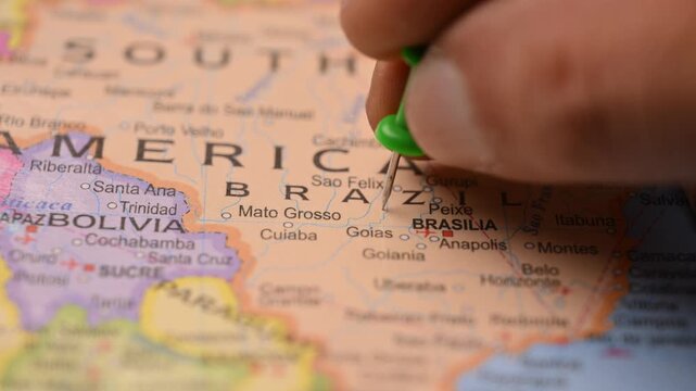 Close-Up World Map Shot Featuring Green Pin Highlighting Brazil Pointed by Hand 4K 60fps