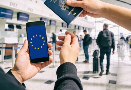 Traveler holding smartphone with European Union flag and American passport at airport terminal, international travel and digital visa concept for immigration and tourism