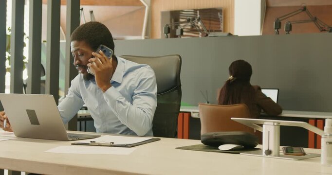 Black marketing manager pitching on phone at workspace
