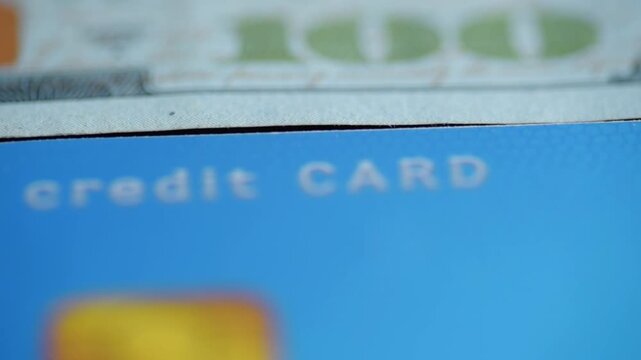 Closeup credit card text credit CARD with hundred dollar bill overlay, vibrant blue field, chip out of focus, rewards and cashback implication, merchant checkout mood, retail