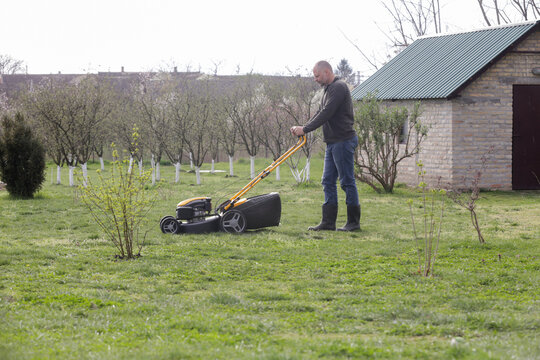 Man Mowing Lawn in Rural Backyard &ndash; Countryside Living and Outdoor Chores Lifestyle