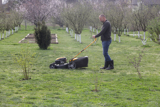 Man Mowing Lawn in Rural Backyard &ndash; Countryside Living and Outdoor Chores Lifestyle