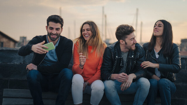Group of Young Adults Laughing Together Outdoors During Sunset