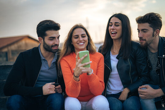 Group of friends enjoying social media on smartphone outdoors, showcasing digital connectivity