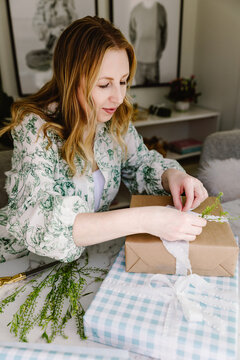 Woman wrapping rustic gift in cozy home
