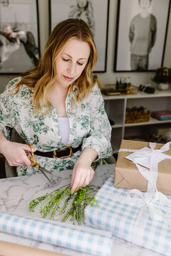 Woman wrapping gifts at marble table