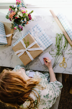Woman wrapping gifts at bright marble table