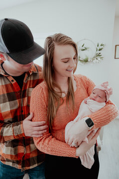 Young mom and dad looking at newborn in mothers arms