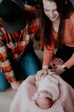 Young mom and dad looking over their newborn baby girl
