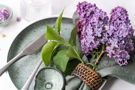 Spring dinner setting decorated with fresh lilac flowers on conc
