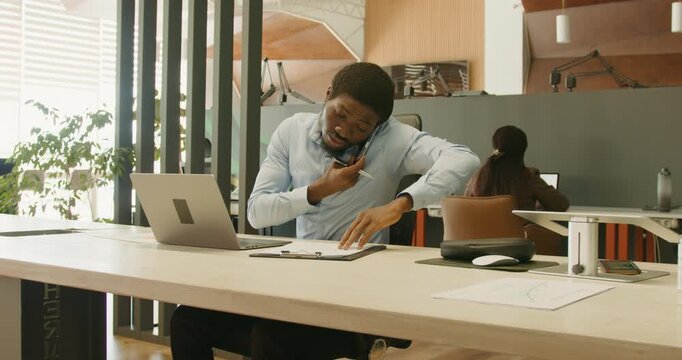 Financial professional signs documents during phone conversation at desk