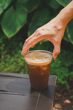 Hand reaching for refreshing iced coffee outdoor garden beverage photography nature
