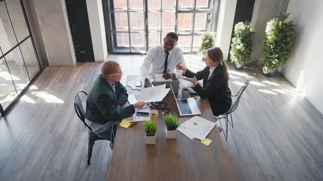 Work of financial department in modern office, professionals discussing project . Multiethnic colleagues working together, diverse people sitting at table and communicating for achieve common goal