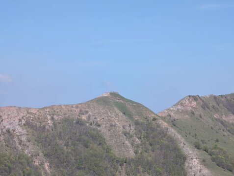 Ripresa panoramica di una cresta montuosa con rocce affioranti e pendii erbosi illuminati dal cielo limpido, in un paesaggio naturale incontaminato