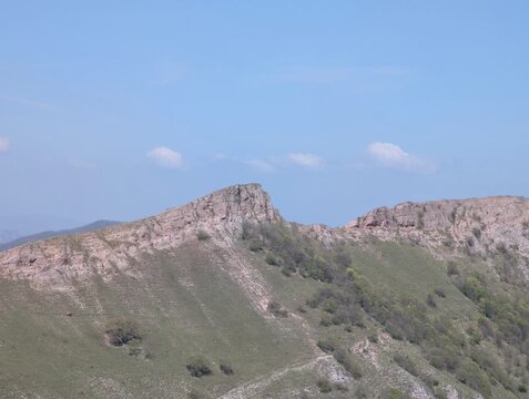 Ripresa panoramica di una cresta montuosa con rocce affioranti e pendii erbosi illuminati dal cielo limpido, in un paesaggio naturale incontaminato