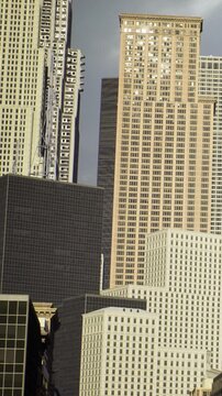 Tall buildings are visible against the sky. The structures show different designs and materials. Sunlight reflects on glass surfaces. This scene captures the essence of urban life.