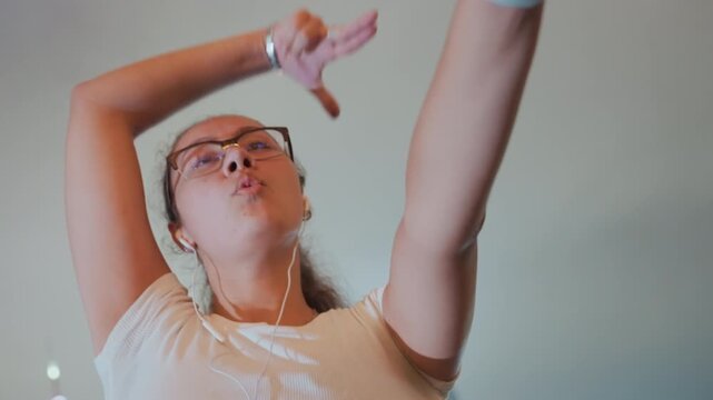 Energetic street dancer under night skyline young woman with glasses earbuds performs powerful routine low angle camera dynamic arm movement neon reflections confident expression urban rhythm