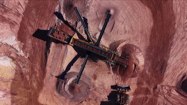 Overhead view of a multi-deck mobile screening plant with radial discharge conveyors separating clay and soil in a red earth open-pit mining quarry