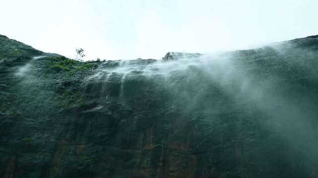 4K slow motion shot of waterfall falling from a cliff as seen while standing directly below it during the monsoon season in the Sahyadri mountain ranges at Maharashtra, India. Scenic view of waterfall