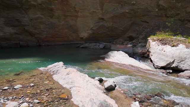 Closeup shot of a scenic river stream flowing in between rocks in the Himalayan mountains as seen near Manali in Himachal Pradesh, India. Beautiful water stream in mountains. Scenic background.