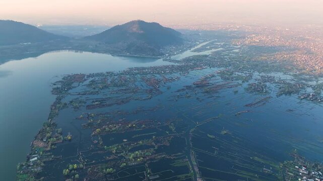 Aerial sweep of Dal Lake floating gardens and Srinagar cityscape.