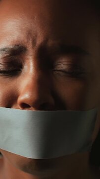 Hostage, fear and face of woman with tape for silence, vulnerable and victim of domestic violence. Abuse, black person and mouth cover on studio background for censorship, kidnap and panic for danger