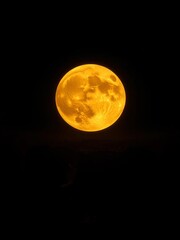 Fototapeta premium Molten gold moon spills over inky horizon, its intense glow etching stark realities of the abyss, luminous, dramatic
