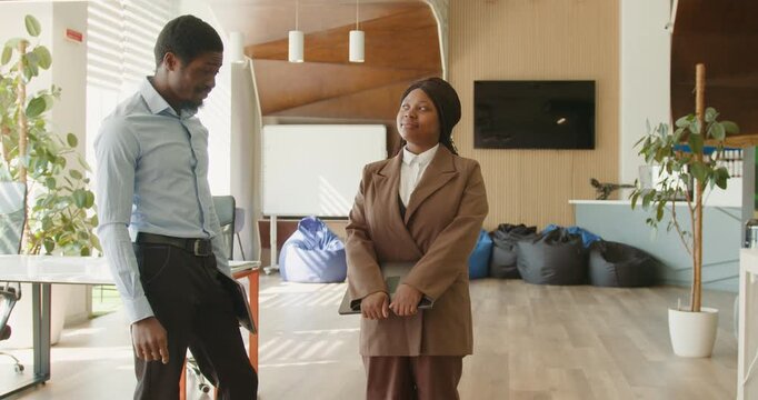 Black mentor guiding black colleague at coworking desk