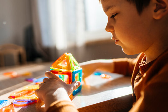 Focused child building house with magnetic toy indoors