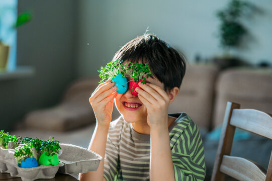 Boy holding easter eggs with microgreens over eyes