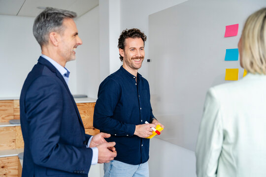 Business meeting in a modern office with three people smiling and discussing ideas