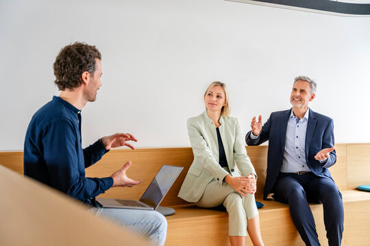 Business meeting in a modern office with three people engaged in discussion
