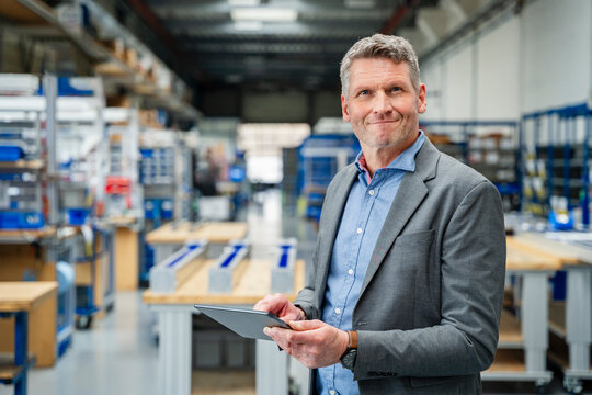 Smiling manager holding a tablet in a production hall