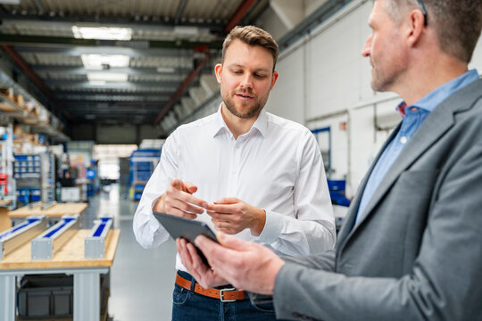 Manager discussing production with engineer using tablet indoors