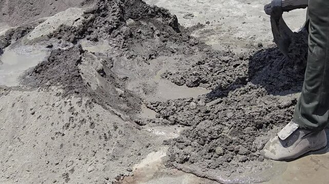 A worker uses a shovel to manually blend cement, sand, and aggregate on-site. This essential process creates a consistent concrete or mortar mix, ensuring strength for floors and structural projects.